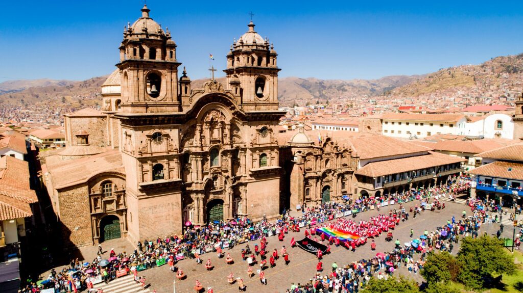 A vibrant parade in front of the Church of the Society of Jesus in Cusco, Peru.