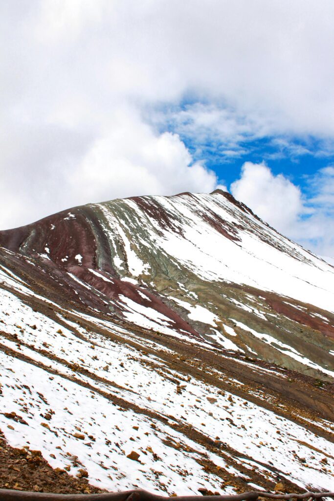 Stunning view of the snow-dusted Rainbow Mountain under a vibrant blue sky in Cusco, Peru.