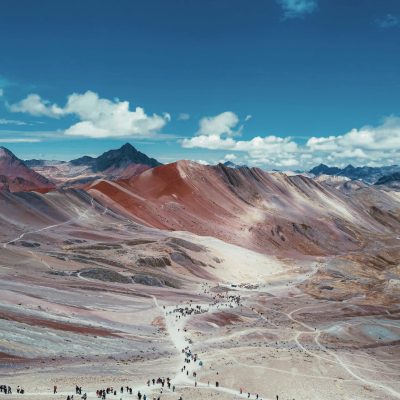 Stunning view of a colorful mountain landscape with hikers on a trail under a vivid blue sky.