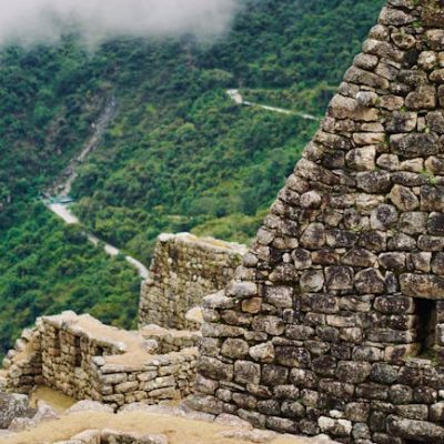 Explore the ancient stone ruins in Aguas Calientes, Peru, amidst lush mountains and misty clouds.