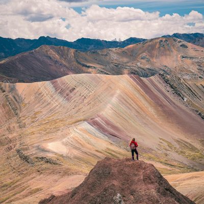 Adventurous hiker atop the vibrant peaks of Rainbow Mountain, Peru during daytime.