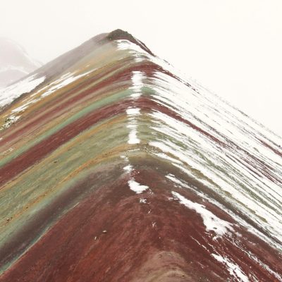 Stunning high-altitude shot of Peru's iconic Rainbow Mountain with snow-capped peaks.