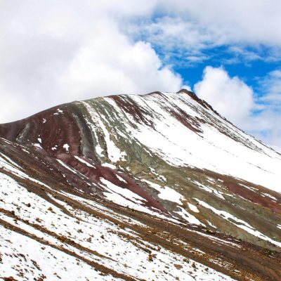 Stunning view of the snow-dusted Rainbow Mountain under a vibrant blue sky in Cusco, Peru.